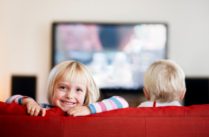 photo of smiling child on lounge with TV in background